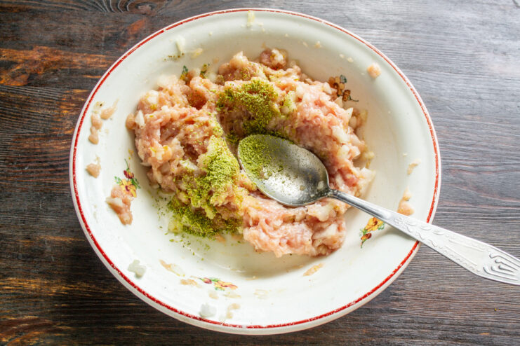 Seasoning the Minced Meat with Spices Seasoning raw minced meat in a bowl with dried dill and pepper.