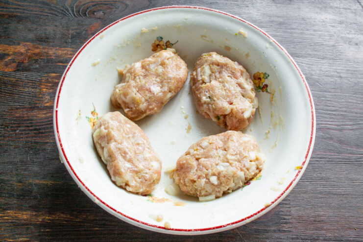 Forming Oval Meat Patties by Hand Hands forming an oval-shaped patty from a mixture of seasoned minced meat.