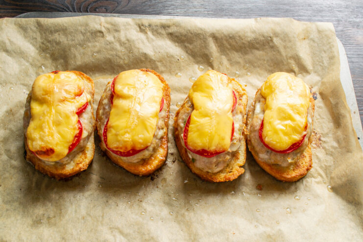 Placing the Sandwiches in the Oven to Bake A baking sheet with assembled open-faced sandwiches being placed into an oven.