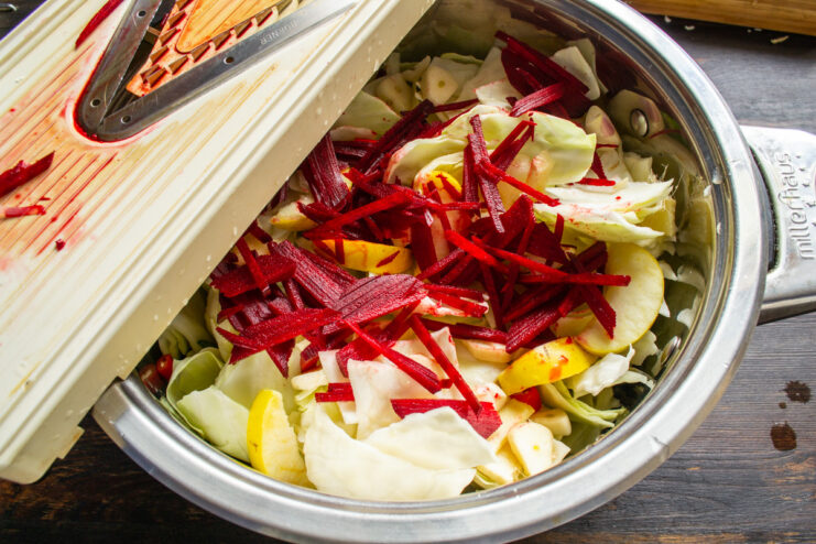 For a Vibrant Color: Shredding Beets into Julienne Strips A raw beet being shredded into thin, julienne-style strips.