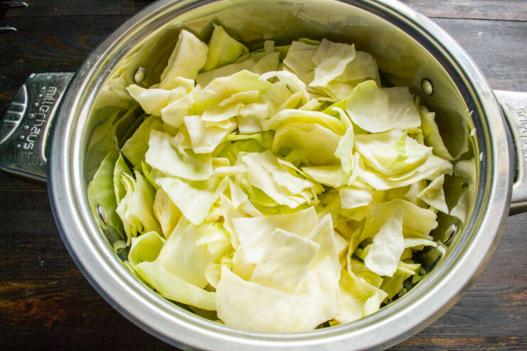 Preparing the Cabbage: Adding Chopped Pieces to a Large Pot A large metal pot filled with coarsely chopped white cabbage.