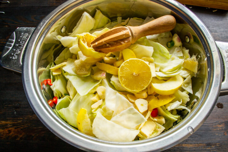 Adding Acidity: Squeezing Fresh Lemon Juice into the Mix Hand squeezing a lemon to add fresh juice to the bowl of vegetables.