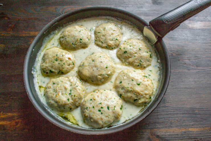 Final Step: Simmering the baked cutlets in the sauce Baked chicken cutlets simmering gently in a creamy milk sauce in a skillet.