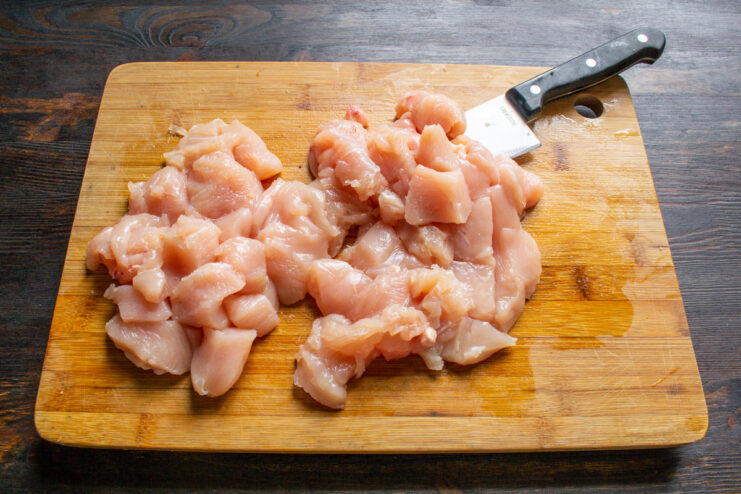 Step 1: Dicing the chicken fillet for the cutlets Close-up of chicken breast fillet being diced into small cubes on a cutting board.