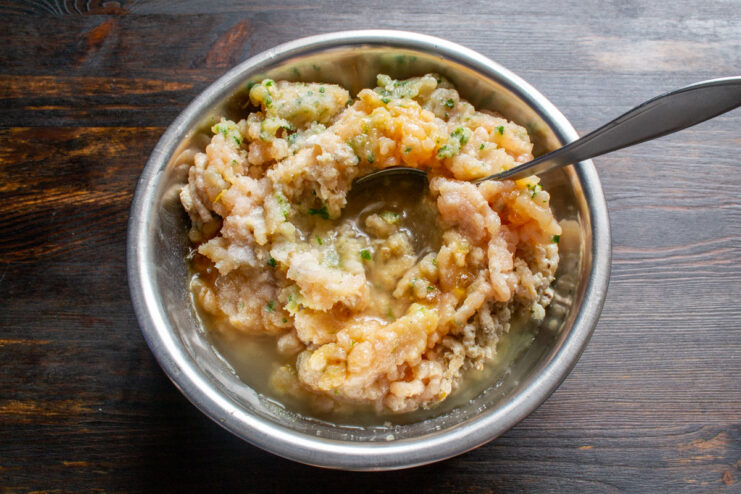 Step 3: Adding chicken broth to the minced meat Pouring cold chicken broth into a bowl with minced chicken.