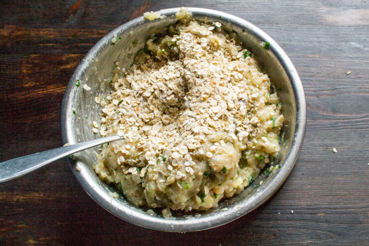 Step 4: Adding quick-cooking oats to the mixture Adding quick-cooking rolled oats to the minced chicken mixture in a bowl.