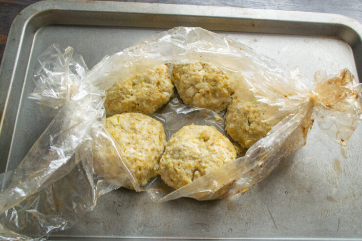 Resting the Baked Chicken Patties A baking sheet with cooked chicken patties inside a roasting bag, fresh out of the oven.
