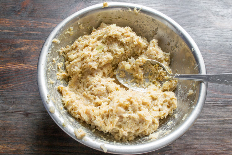 Kneading the Ground Meat for Patties Hands thoroughly mixing the ground chicken, oats, and spices in a bowl.
