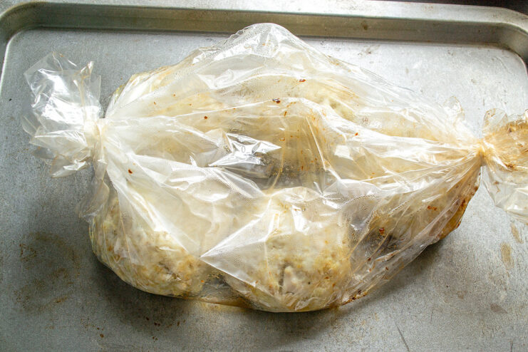 Arranging Patties in a Roasting Bag Raw chicken patties arranged inside a clear roasting bag on a baking sheet.