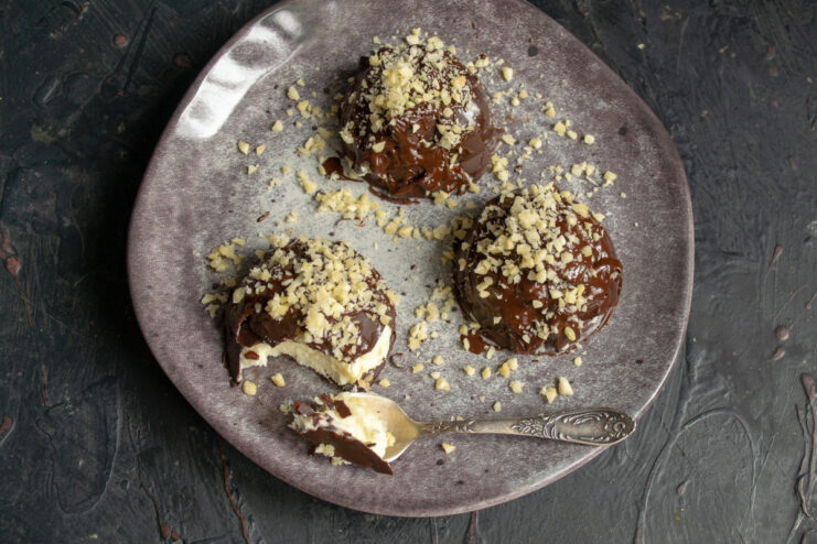 Decorating Glazed Mascarpone Bars with Ganache and Almonds Finished glazed mascarpone bars being decorated with a drizzle of chocolate ganache and chopped almonds.