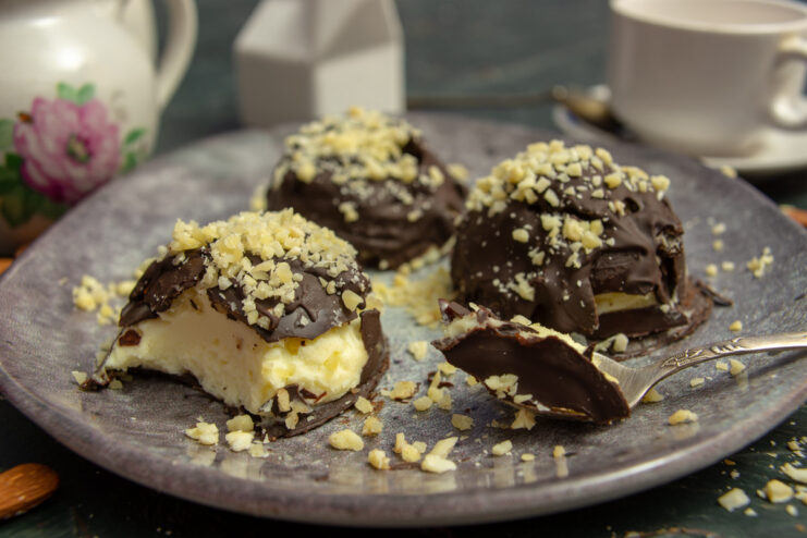 Homemade glazed mascarpone bars on a plate, decorated with almonds and chocolate ganache.