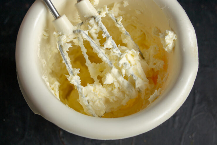 Mixing Mascarpone and Powdered Sugar for the Filling A bowl with mascarpone, powdered sugar, and vanilla being mixed until smooth and creamy.