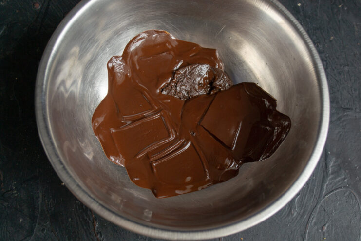 Properly Melting Dark Chocolate for a Glossy Coating Dark chocolate pieces melting in a bowl over a pot of water (water bath).
