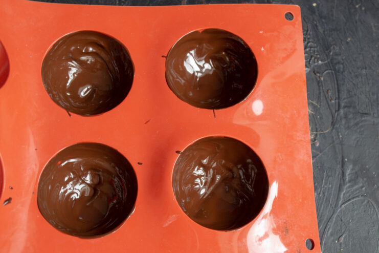 Creating the Chocolate Shell in a Silicone Mold A silicone mold being coated with a thin layer of melted dark chocolate.