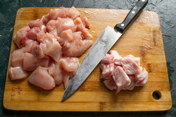 How to Dice Pork for Sausage Filling Close-up of pork being diced into small cubes on a wooden cutting board.