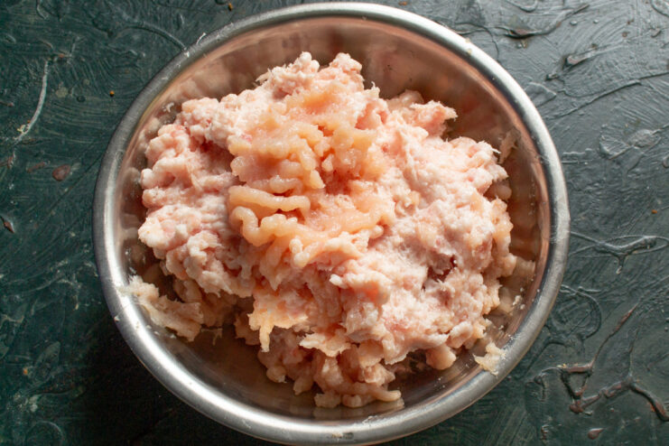 Grinding Meat for the Perfect Sausage Texture A meat grinder processing chicken, pork, and shpek into a fine mince for sardelki.