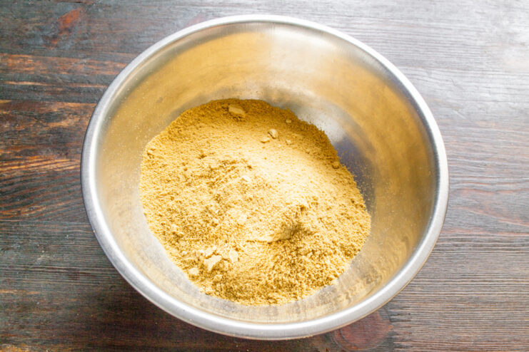 Measuring Mustard Powder for the Recipe A bowl of yellow mustard powder with a spoon, ready for making homemade mustard.