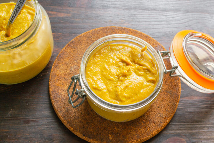 Storing Homemade Mustard for Flavor Development Transferring the finished homemade mustard into a clean glass jar for storage.