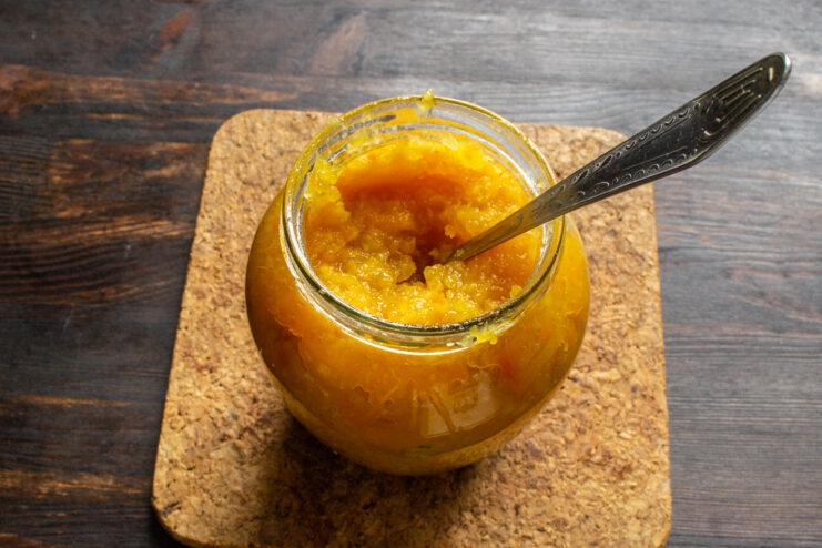 Canning the hot pumpkin jam into sterilized jars Hot pumpkin jam being ladled into a clean glass jar for preservation.