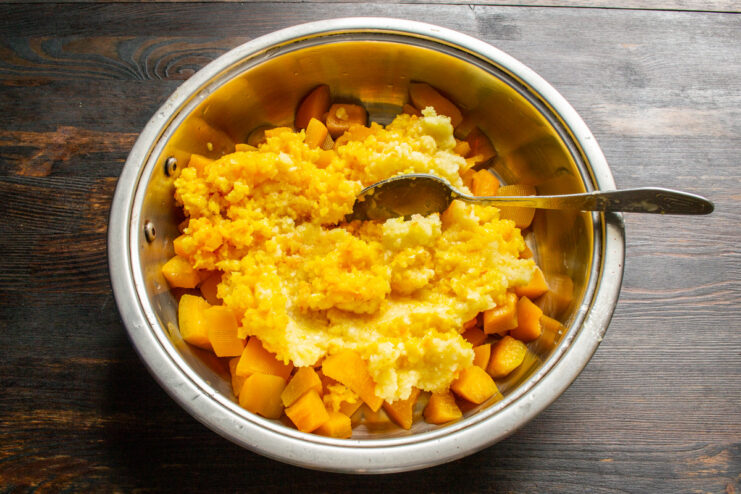 Combining pumpkin with apple and orange puree A saucepan with diced pumpkin topped with a bright orange puree of apples and oranges.