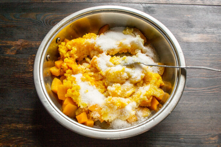 Adding sugar to the pumpkin and fruit mixture Granulated sugar being poured into the saucepan with the pumpkin and fruit puree.