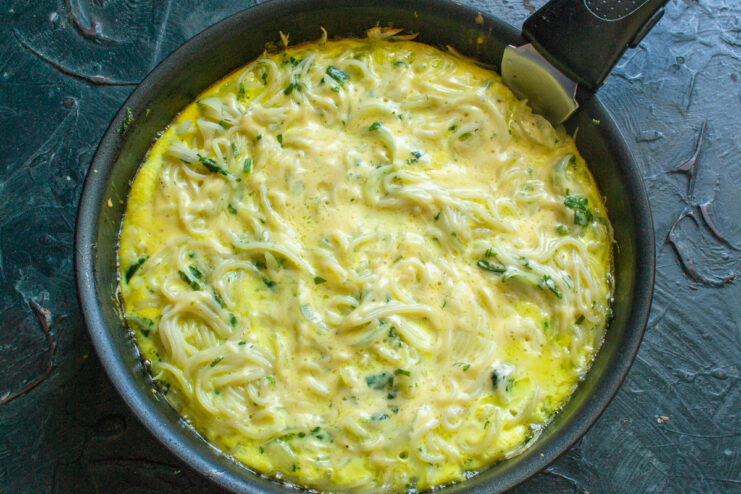 Cooking the Frittata on the Stovetop Until Set A skillet with frittata cooking on the stove, covered with a glass lid.