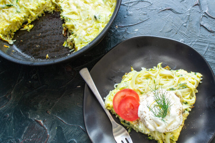 Serving the Freshly Cooked Frittata with Garnish A finished slice of frittata on a plate, garnished with dill and served with fresh tomatoes.