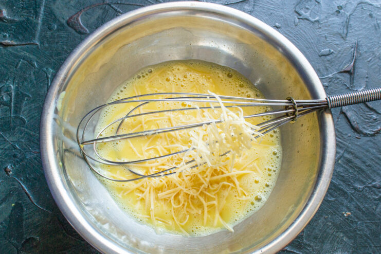 Grating Hard Cheese to Add Flavor to the Frittata A block of hard cheese being grated on a metal box grater.