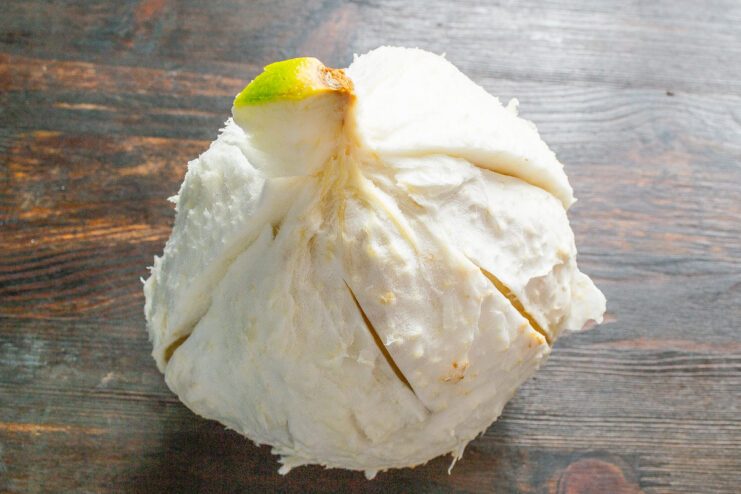 How to easily peel a pomelo for a fruit salad A person's hands peeling the thick skin off a large pomelo fruit.