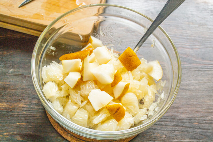 How to dice a pear for a fruit salad A ripe pear being diced into small cubes on a cutting board.