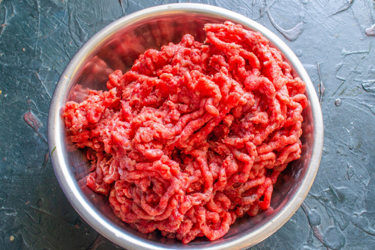 Grinding Beef for the Sauce - Use lean beef for the best flavor. Close-up of lean beef being processed through a meat grinder to make mince.