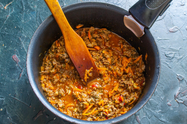 Seasoning the Sauce - Adjust salt and pepper to your liking. The finished meat and vegetable sauce simmering in a pan.