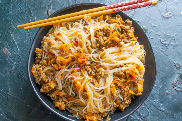 Serving the Funchoza - Garnish with a drizzle of olive oil. A serving of funchoza with minced meat in a large bowl, drizzled with olive oil.