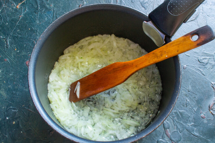 Finely Chopping the Onion - The base for a flavorful sauce. A pile of finely chopped white onion on a cutting board.