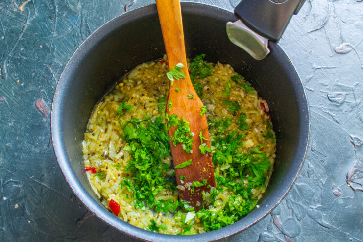 Adding Fresh Cilantro - For a burst of fresh, herbal flavor. Chopped fresh cilantro being added to the sautéed onions in a pan.