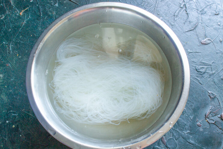 Soaking the Funchoza Noodles - An easy way to prepare glass noodles. Dry funchoza noodles in a white bowl with boiling water being poured over them.
