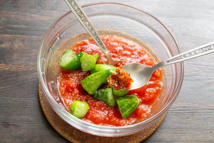 Seasoning the Gazpacho with Sea Salt and Spicy Adzhika A spoonful of red spicy adzhika paste and sea salt being added to the gazpacho ingredients.