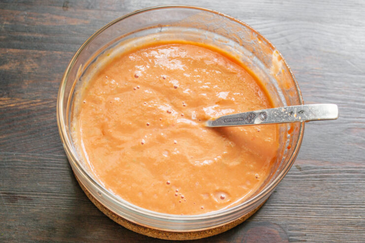 How to Thicken Gazpacho Naturally with Stale Bread Finely crumbled stale white bread being added to the bowl of gazpacho ingredients.