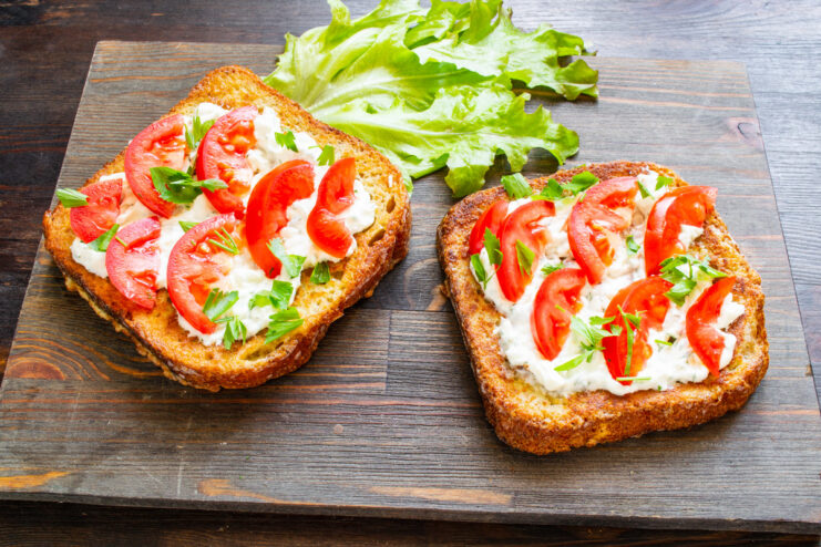 Garnishing the Hot Sandwiches with Fresh Parsley Sprinkling chopped fresh parsley over hot sandwiches with tomatoes.