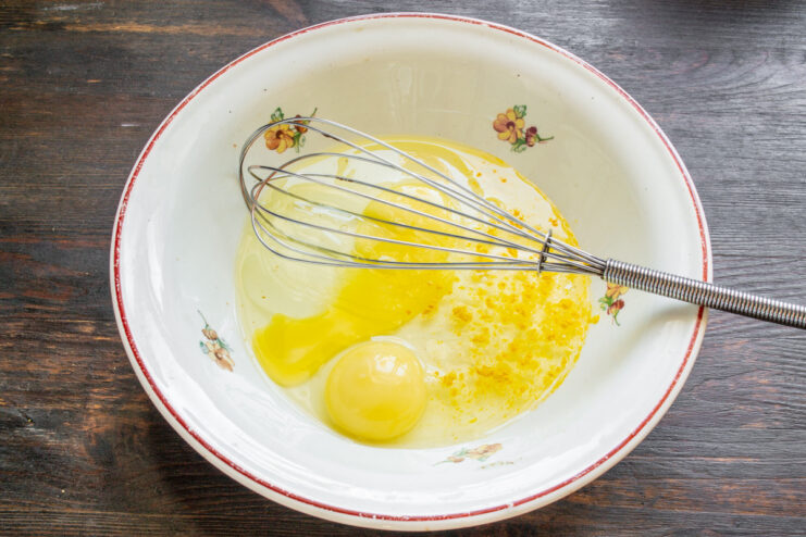 Preparing the Egg Mixture for the Sandwich Base Two chicken eggs cracked into a shallow white bowl.