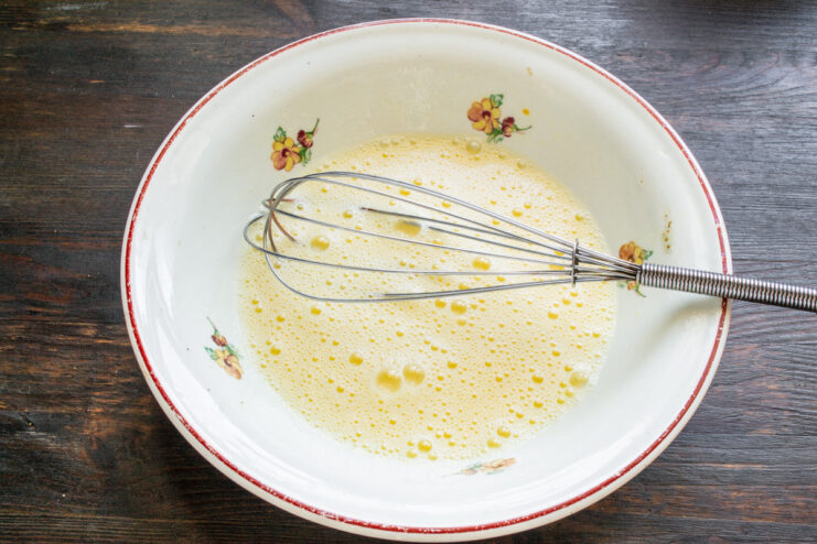 Whisking Eggs and Milk for a Perfect French Toast Batter Whisking eggs and milk in a white bowl to create a smooth mixture.