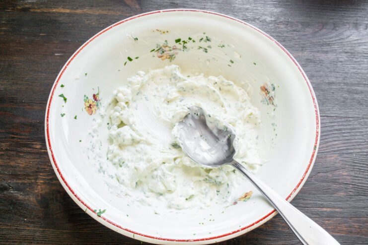 Seasoning the Cream Cheese Spread with Sea Salt Mixing a white creamy spread in a bowl with a spoon.