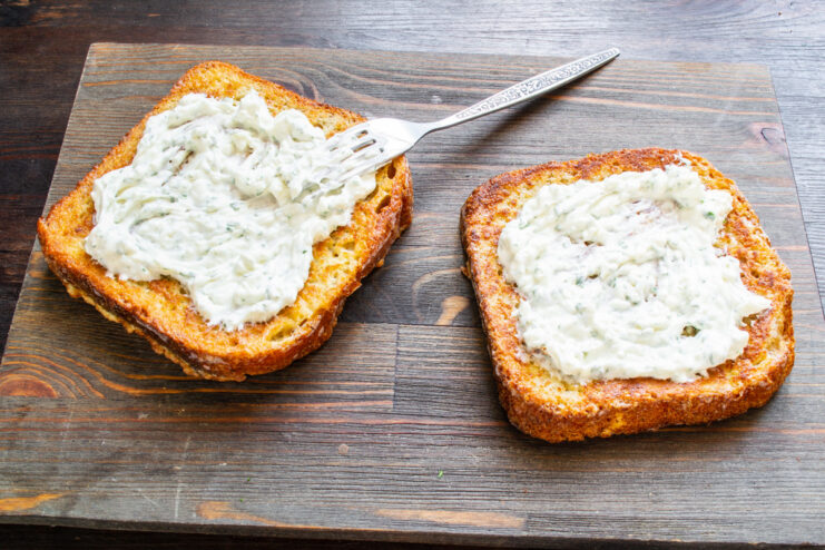 Spreading the Savory Cream Cheese Mixture on the Fried Bread Spreading a creamy white mixture over a slice of golden-fried bread.
