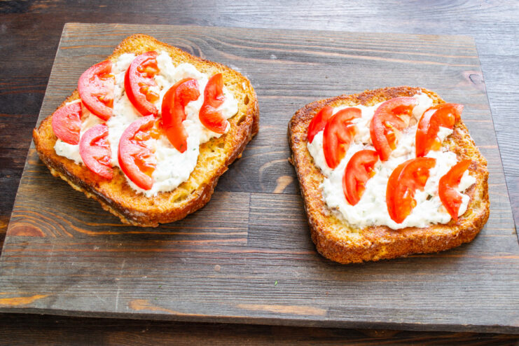 Topping the Sandwiches with Freshly Sliced Tomatoes Placing fresh tomato slices on top of the cream cheese spread on a sandwich.
