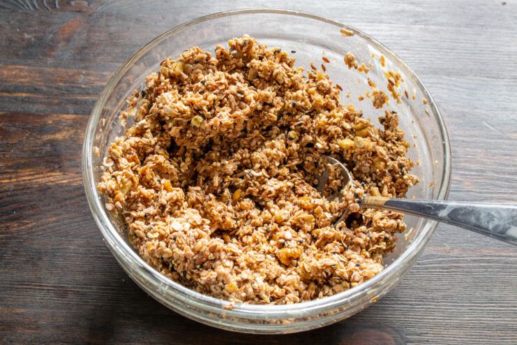 Mixing Everything Until Well Combined A spatula mixing all the wet and dry granola ingredients in a bowl.