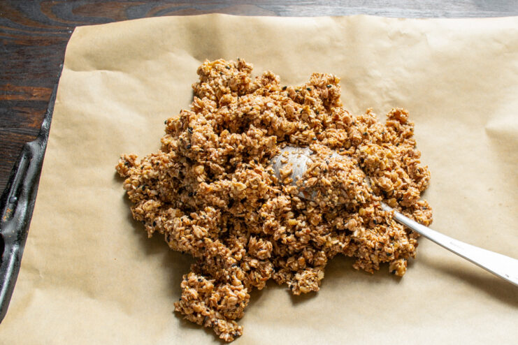 Spreading the Granola Mixture on a Baking Sheet Spreading the wet granola mixture onto a parchment-lined baking sheet.