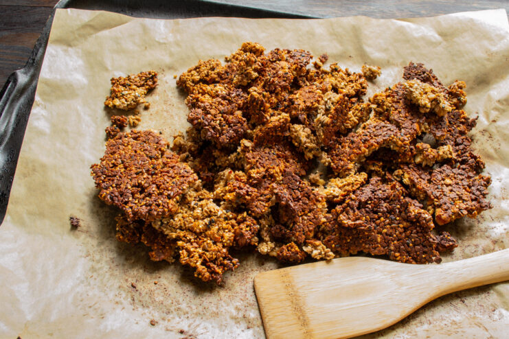 Cooling and Breaking the Granola into Clusters A sheet of baked granola being broken into smaller, bite-sized clusters.