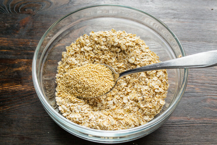 Adding Quinoa for Extra Protein and Crunch Adding uncooked quinoa to the bowl with rolled oats.
