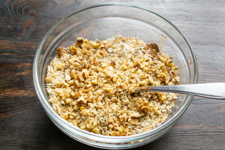 Incorporating Chopped Nuts for Healthy Fats Adding chopped walnuts to the bowl of dry granola ingredients.