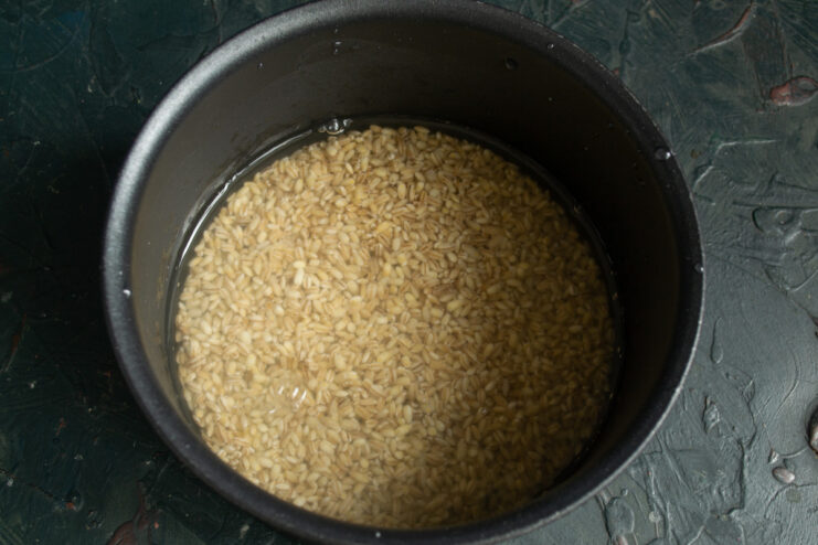 Cooking pearl barley separately ensures the soup stays clear and perfectly textured. Pearl barley cooking in a small pot with water on the stove.